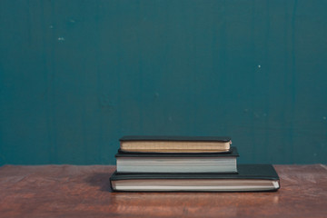 three closed notebooks on wooden desk isolated