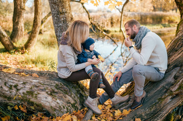 Happy family couple with their son and little puppy in autumn park