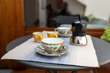 a set of decorated coffee cups with coffemaker, on a table set for breakfast, interior design on a balcony