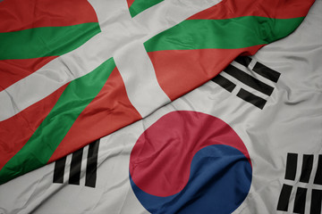 waving colorful flag of south korea and national flag of basque country.