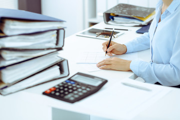 Fototapeta premium Unknown female bookkeeper or financial inspector calculating or checking balance, making report, close-up. Internal Revenue Service at work with financial document. Tax and audit concept