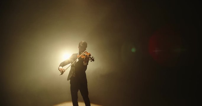 Asian violinist performing on stage. Popular musician playing solo on his his instrument on smoked black background 4k footage