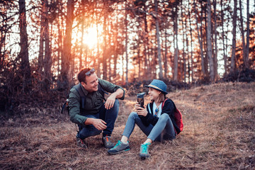 Fototapeta premium Father and daughter resting in forest and drinking water
