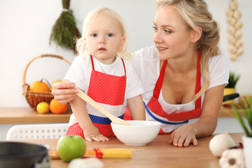 Happy mother and little daughter cooking in kitchen. Spending time all together, family fun concept