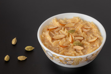 Vermicelli dessert, popular sweet dish know a kheer made with milk and garnish with dry fruits isolated on black gray background, served in bowl. Selective focus. Top view.