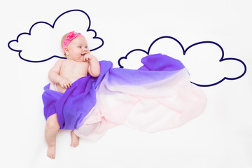 wondering baby girl wrapped in fabric with painted clouds.