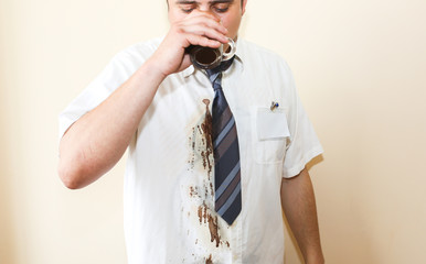 Office worker spills coffee on white shirt. Occupational burnout. Unhappy manager with mug in...
