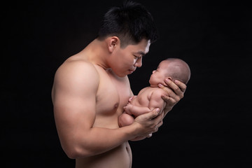The baby sleeps in the hands of a strong father.