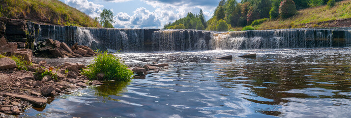 Panorama of waterfall on mountain river on summer day