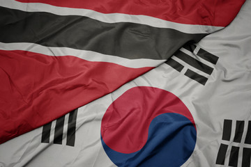 waving colorful flag of south korea and national flag of trinidad and tobago.
