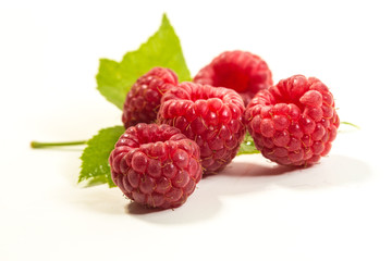 Close up a bunch of fresh raspberries and green leaf isolated on the white