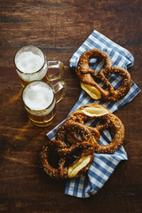 Sesame pretzels and beer glasses on dark brown wooden table. Traditional german appetizer. Oktoberfest background