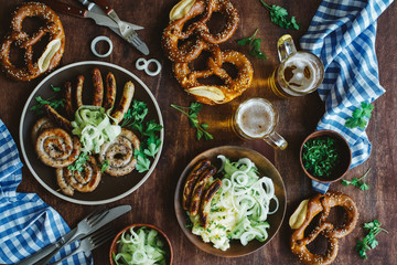 Traditional german appetizer and beer glasses on dark brown wooden table. Mashed potatoes, salad, pretzels and sausages. Oktoberfest party background