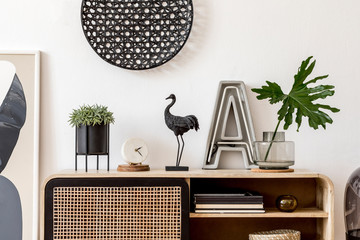 Interior design of living room at nice scandinavian apartment with stylish commode, lamp, rattan...