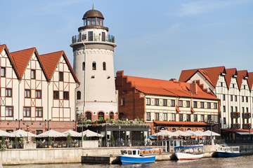 Fototapeta na wymiar Kaliningrad, Russia - August 24, 2019: View of the Fish Village and lighthouse on the embankment of the Pregolya River.