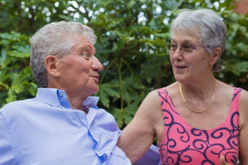 Portrait of an old couple, smiling at each other in outdoor scenery