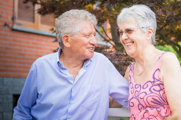 Portrait of an old couple, smiling at each other in outdoor scenery