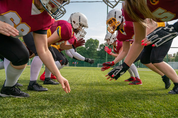Photo of sportrive women wearing helmets playing american football on green lawn