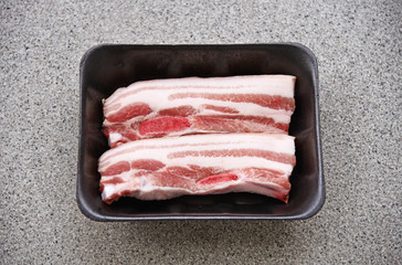 streaky pork in black plastic tray package.