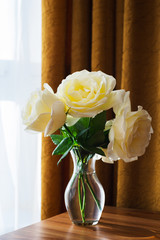 White beautiful rose flowers in a glass vase. Large rose buds with petals.