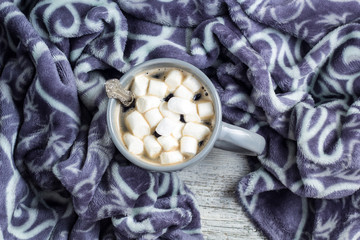 cup of coffee with marshmallows and warm plaid on white wooden table. Christmas Winter concept.