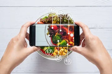 Foto op Plexiglas Calorieën tellen en voedselcontrole concept. vrouw die applicatie op smartphone gebruikt om de hoeveelheid calorieën in het voedsel te scannen voordat ze gaan eten © asiandelight