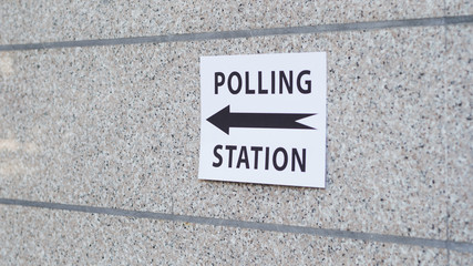 Polling station sign with direction on wall