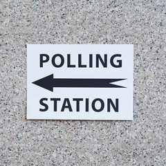 Polling station sign with direction on wall close-up
