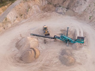aerial view of a quarry with conveyor belt and wheel loader - stones and sands for construction - top view , open pit mine, extractive industry