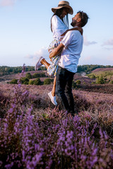 young couple visiting the blooming Heather field Posbank Veluwezoom in the Netherlands, purpple hills with blooming flowers
