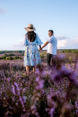 young couple visiting the blooming Heather field Posbank Veluwezoom in the Netherlands, purpple hills with blooming flowers