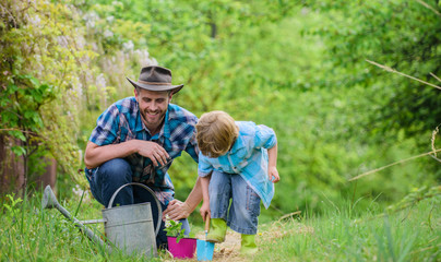 Dad teaching little son care plants. Little helper in garden. Planting flowers. Make planet...