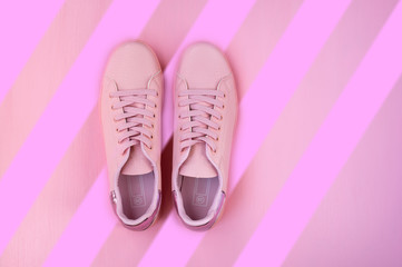 Pink women's sneakers on a pink background. Flat lay, top view.