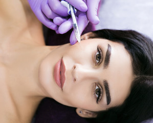 Beauty injections close up. A beautiful mid-aged brunette gets injections of beauty, anti wrinkles therapy, skin rejuvenation