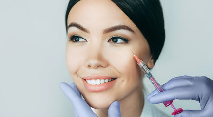 Beautiful Asian woman gets beauty injections. Close-up injection of anti-aging and wrinkle perfect female face