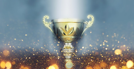 sports concept low key image of gold trophy over dark smoky background and glitter lights