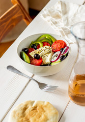 Greek salad on a white wooden background. Tomatoes, peppers, olives, cheese, onions. Healthy eating. Diet. Vegetarian food.