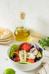 Greek salad on a white wooden background. Tomatoes, peppers, olives, cheese, onions. Healthy eating. Diet. Vegetarian food.