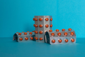 Orange pills in blister packaging with separators. Blue background.