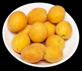 Ripe apricot in a white plate on a black background