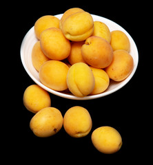 Ripe apricot in a white plate on a black background