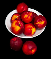 Ripe nectarine in a white plate on a black background