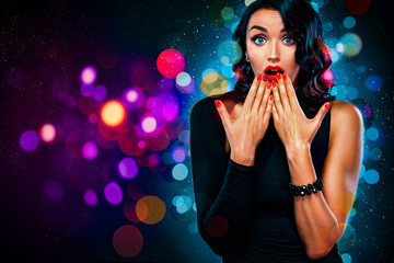 Beautiful, surprised woman with shining makeup and red lips on background with lights was surprised. Girl celebrates New Year 2020 in winter. Shopping, black friday and sale concept.