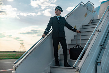 Attractive pilot in uniform standing on airplane ladder