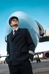 Calm male pilot in uniform waiting for flight in airport