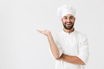 Happy young chef posing isolated over white wall background in uniform showing copyspace.