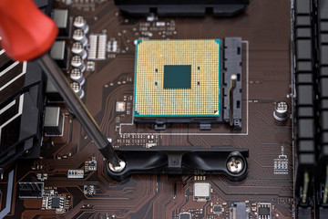 Fototapeta premium Screwdriver screw bolt on motherboard. Close up