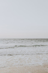 Beautiful tropical beach view with white sand and beige sea with waves on Phuket, Thailand. Minimal composition with neutral colors. Summer concept. Natural background.