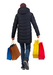 back view of man in winter jacket with shopping bags.