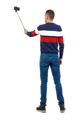 back view of standing young guy with smartphone in the hands of.